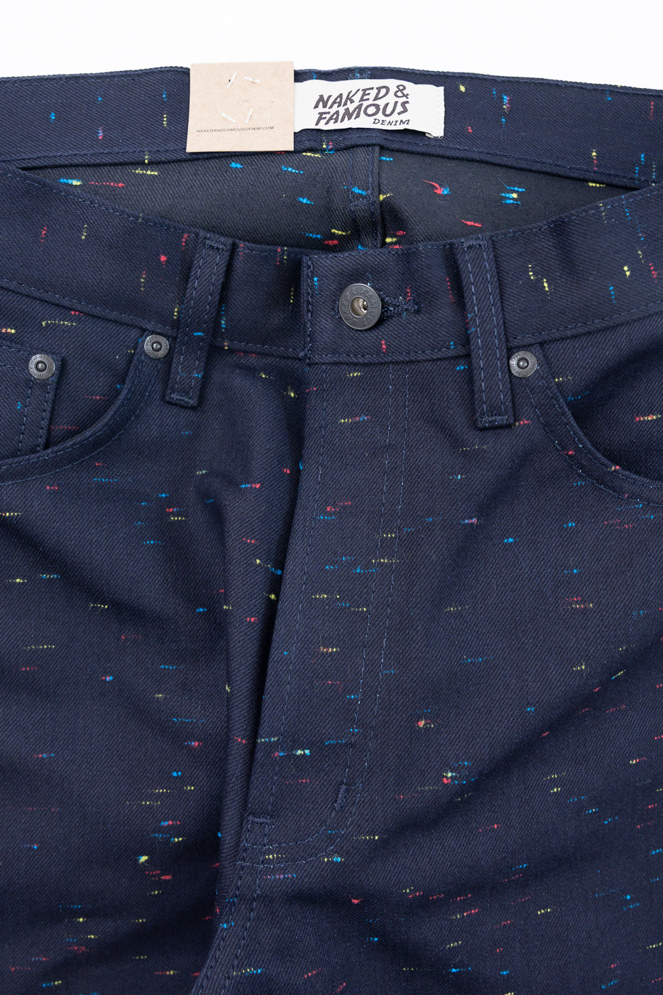 Close-up front view of Naked & Famous denim pants showing button fly and fabric texture.