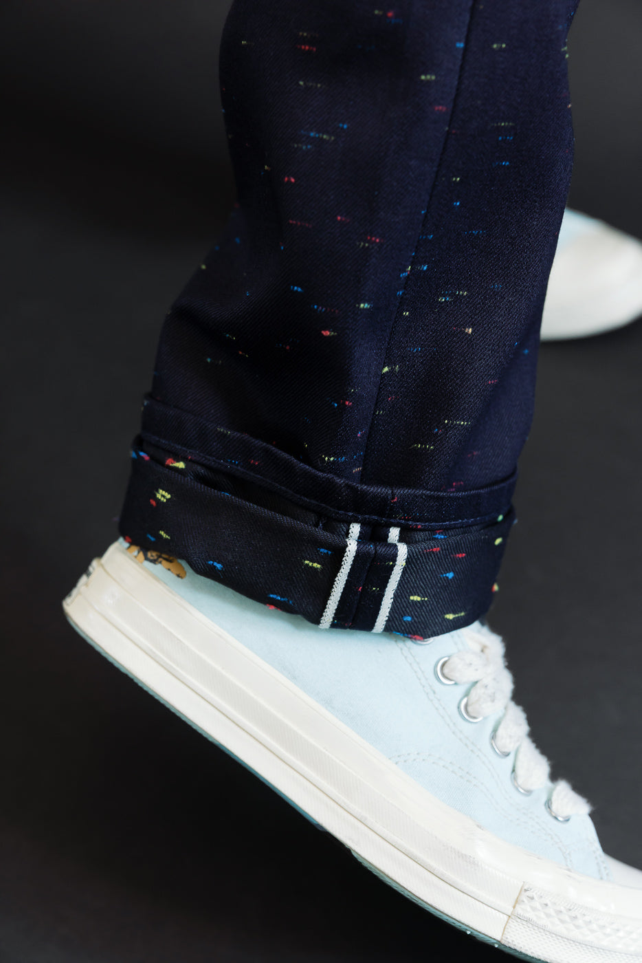 Close-up of the hem and selvedge on navy trousers worn by a 5'9