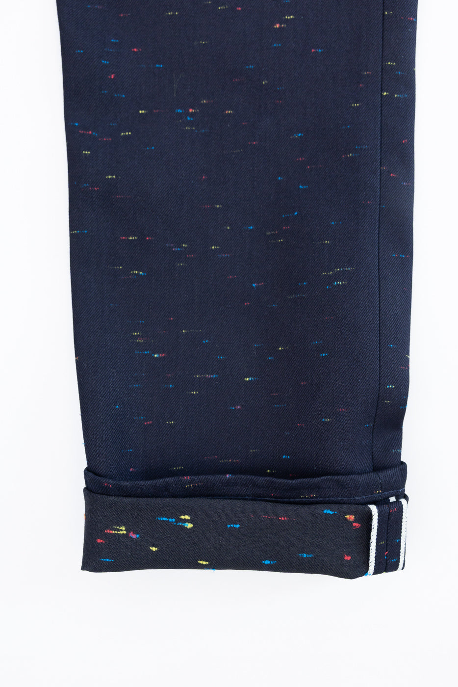 Close-up of the bottom hem and cuff of navy blue patterned trousers showing fabric texture.