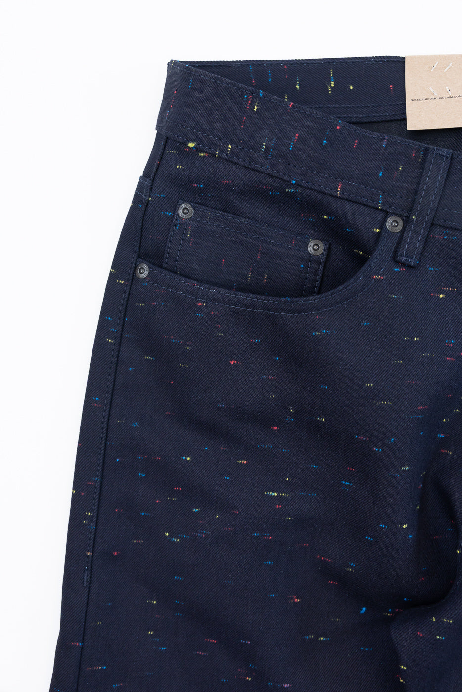 Close-up of the front waist and pocket of navy blue speckled selvedge denim pants.