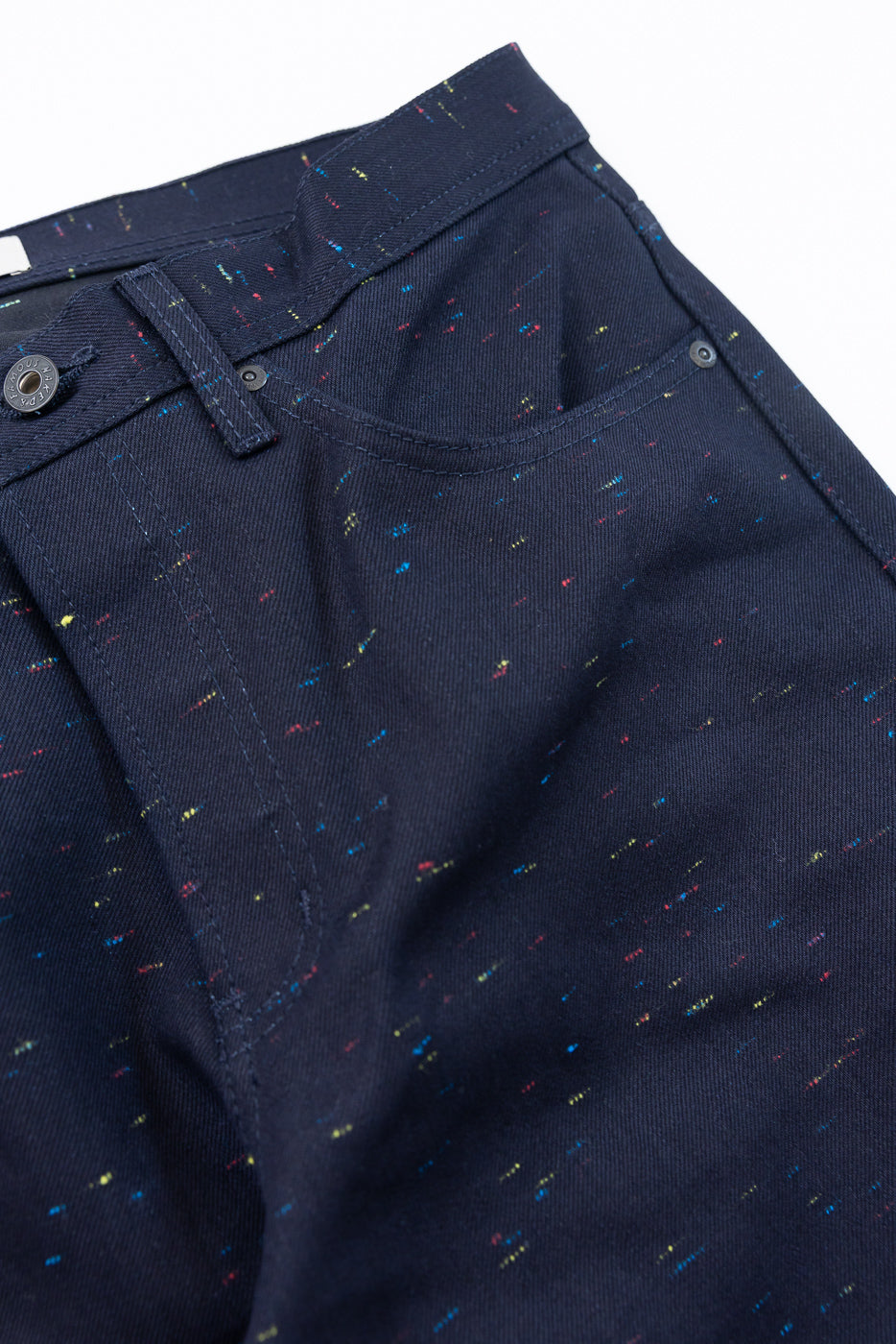 Close-up of the front waistband and pocket of navy blue speckled fabric pants.