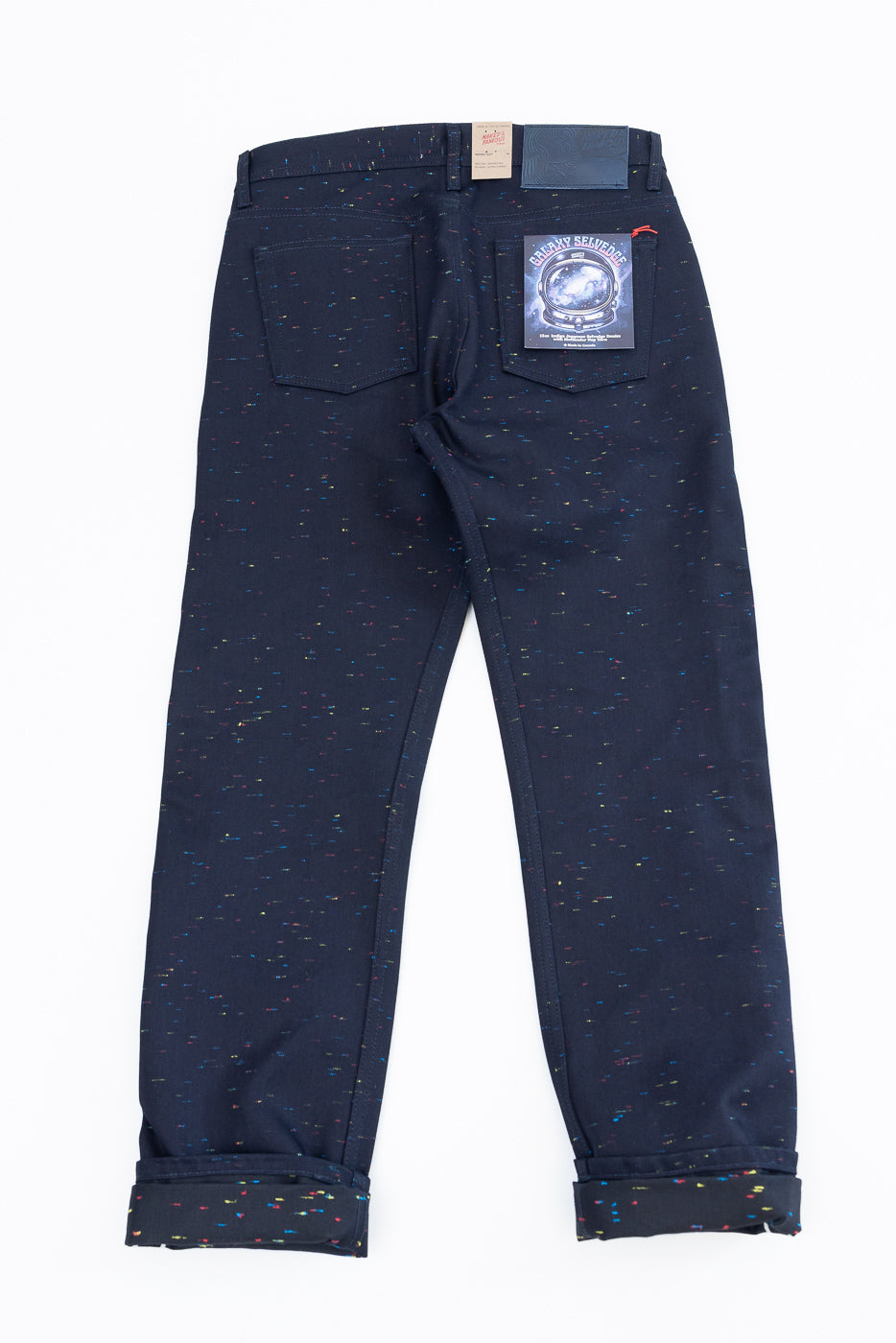Back view flat lay of navy speckled selvedge denim pants with rear pocket and brand tag.
