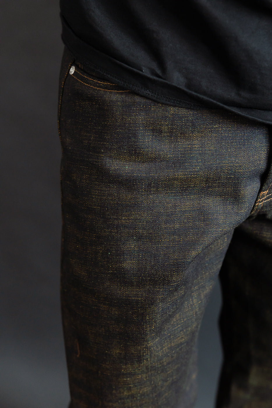 Close-up of male model’s front left upper thigh in 14oz selvedge denim jeans, showing texture and pocket detail. Model is 5'9