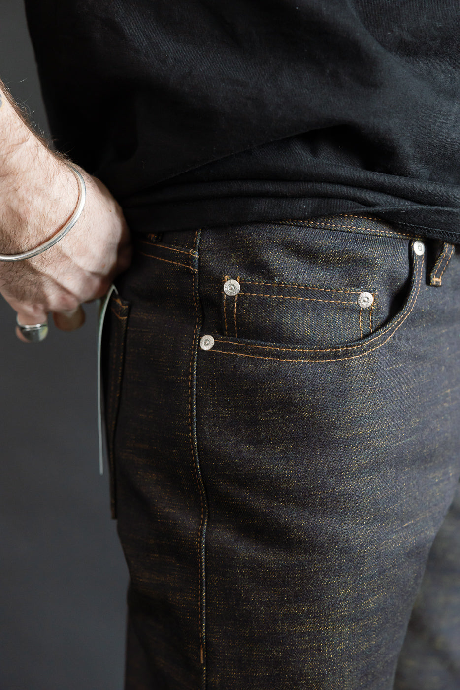 Close-up of men's selvedge denim jeans, back right pocket detail, worn by 5'9