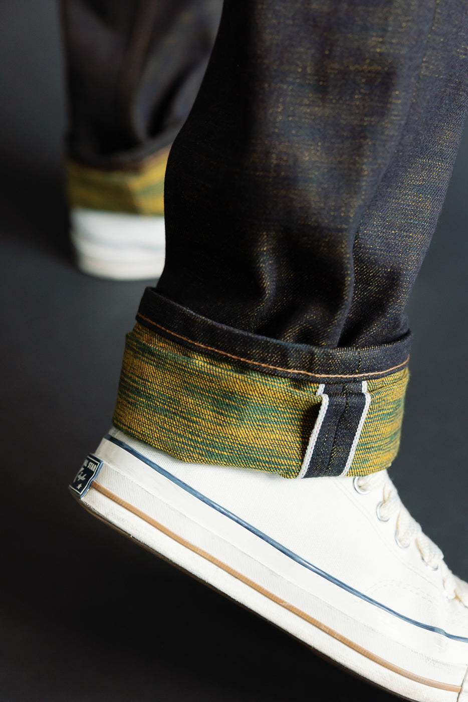 Close-up of men's selvedge denim cuff with yellow-green weft, side view on ankle.