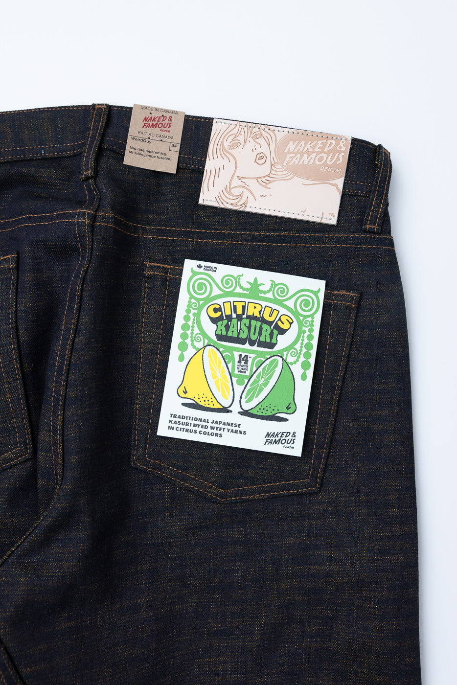 Close-up of back side of men's selvedge denim jeans showing rear pockets, leather patch, and product tags