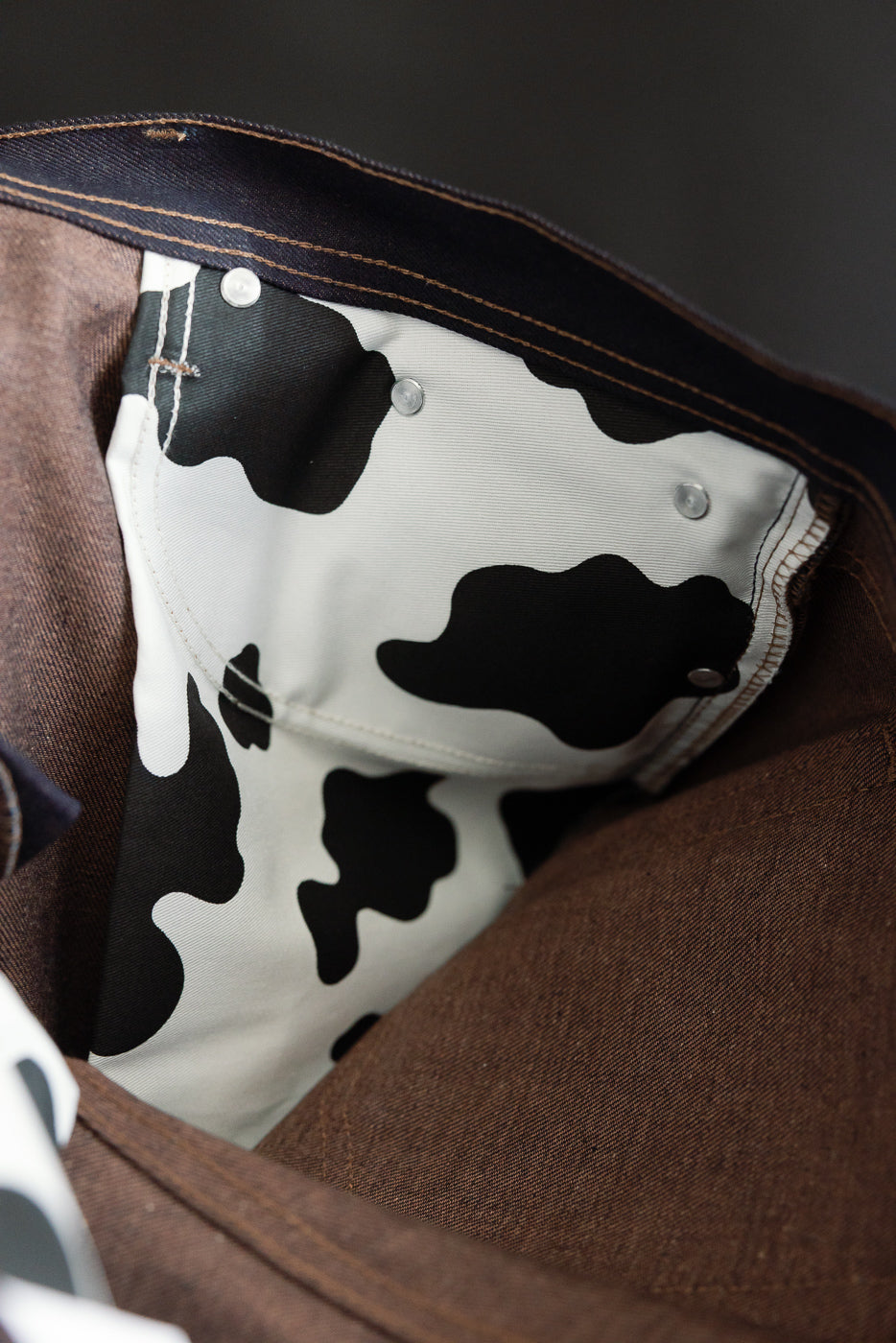 Close-up of selvedge jeans interior, showing cow print pocket lining and brown denim.