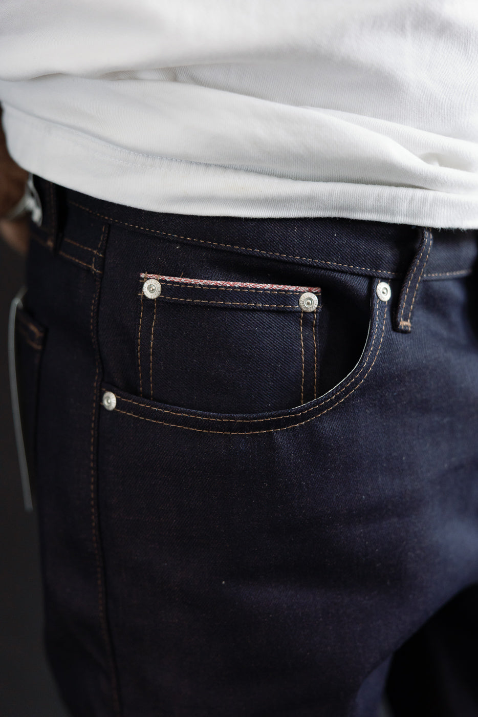 Close-up of men's selvedge denim jeans front pocket, visible stitching, male model 5'9 165lbs athletic build