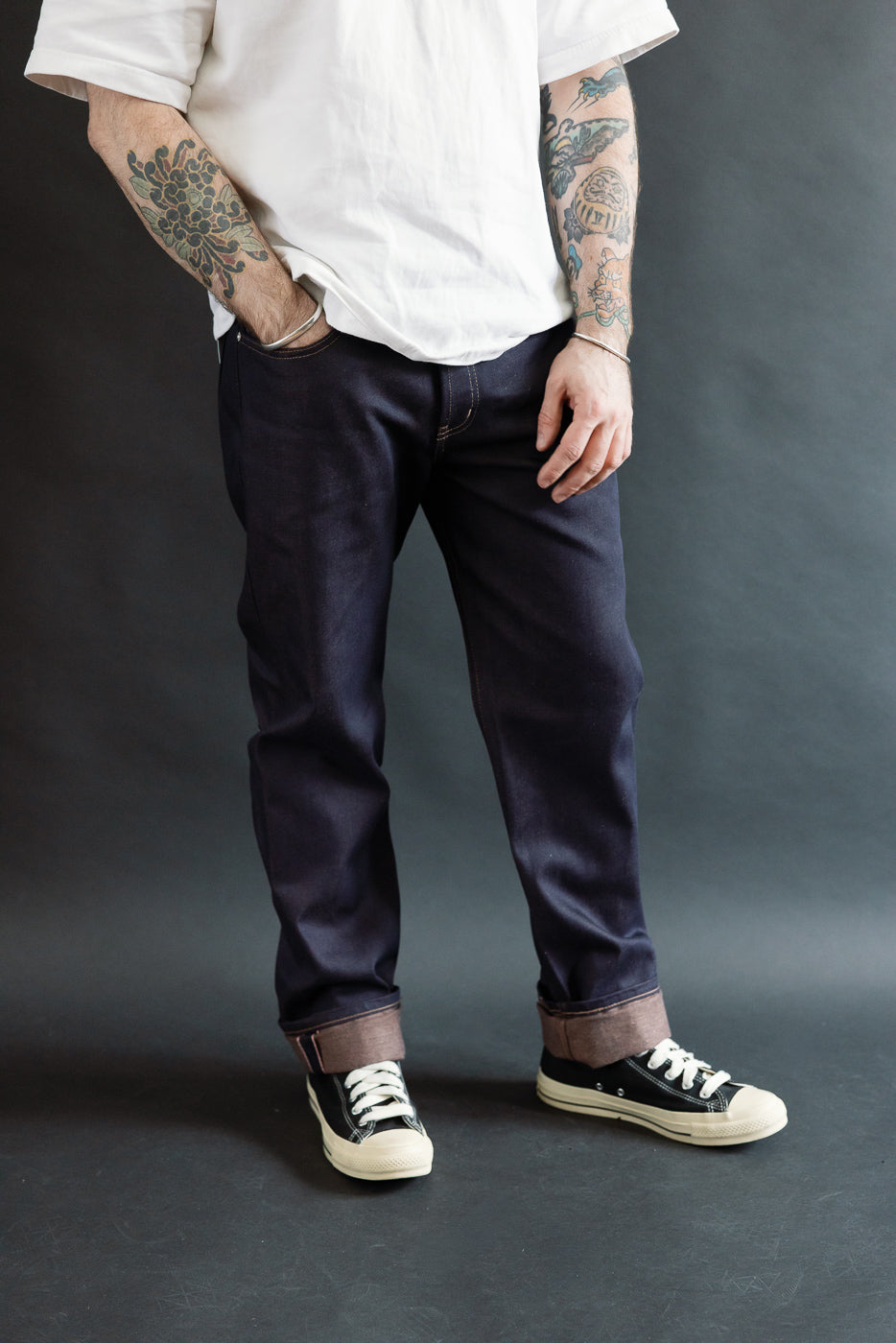 Front view, male model 5'9 165lbs athletic build, wearing dark selvedge jeans, cuffed hem