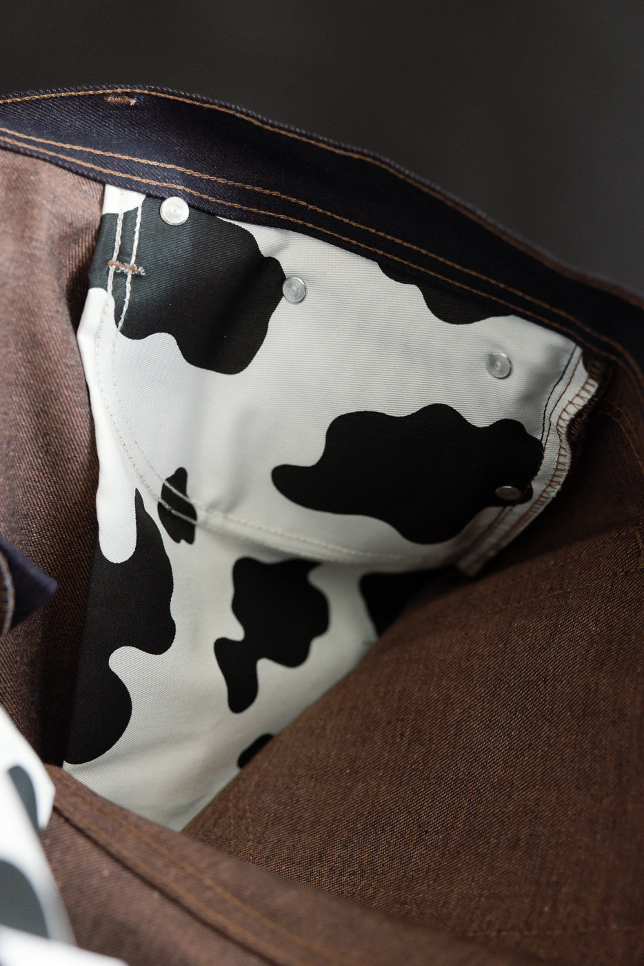 Close-up of inside front pocket lining with black and white cow print detail on brown selvedge jeans.