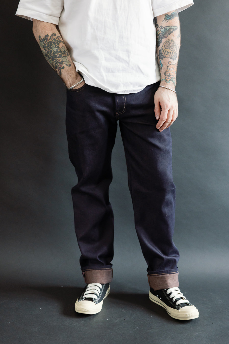 Front view cropped full body of male model 5'9, 165lbs, athletic build in cuffed dark selvedge jeans