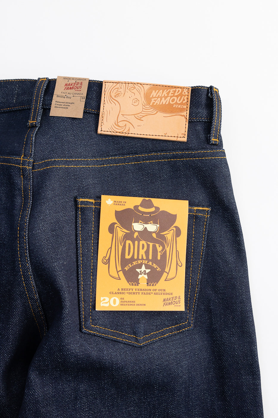 Close-up of Naked & Famous Dirty Elephant 14oz selvedge denim jeans, back side, showing leather logo patch, rear pocket, and product tag detail.
