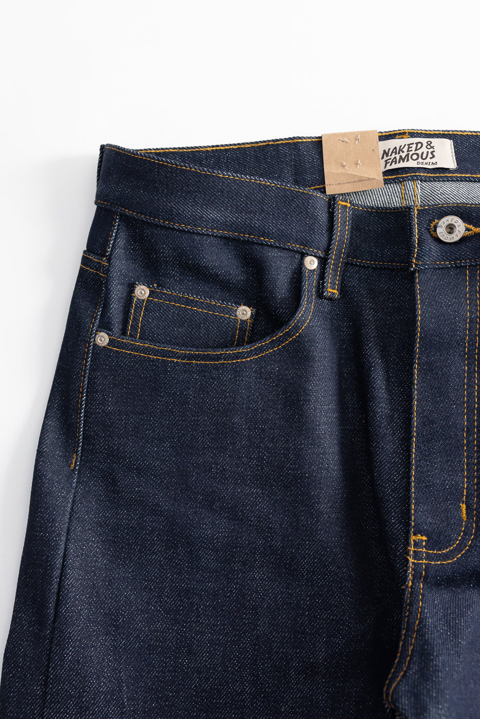 Close-up front view of Naked & Famous selvedge jeans, denim texture, coin pocket, and button detail