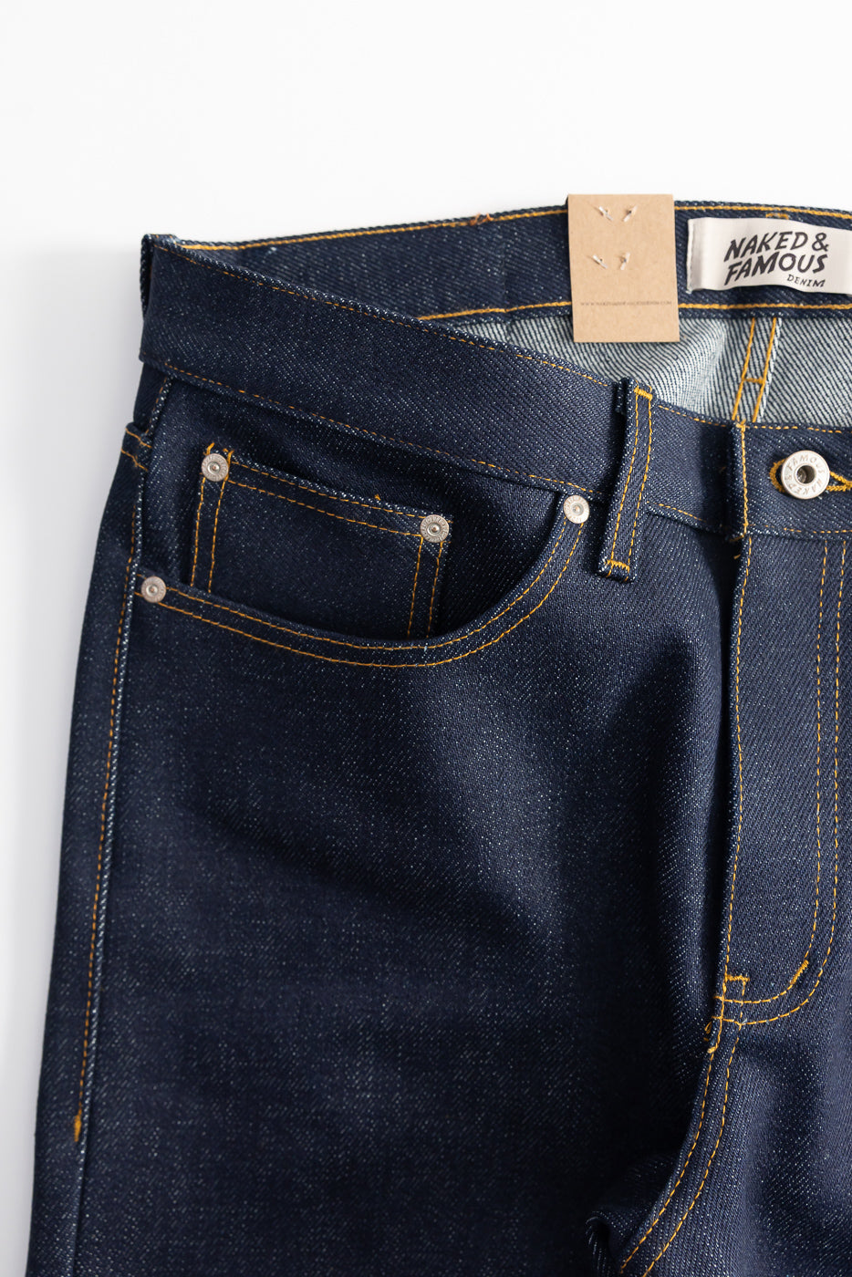 Close-up front view of Naked & Famous selvedge denim jeans, showing pockets, rivets, and waistband details.