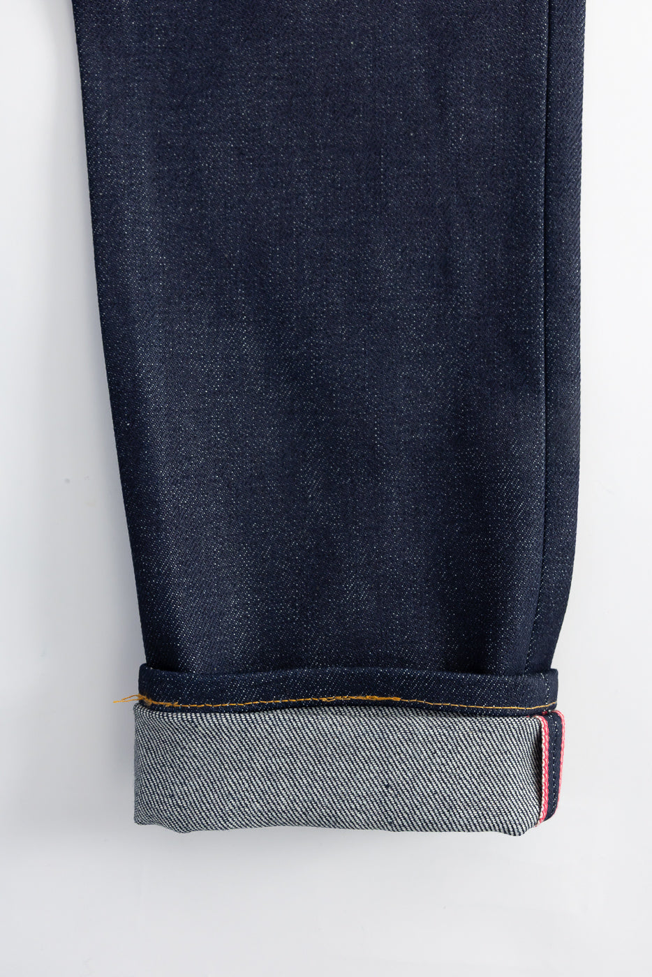 Close-up of cuffed selvedge denim pant leg, highlighting red selvedge ID and fabric texture