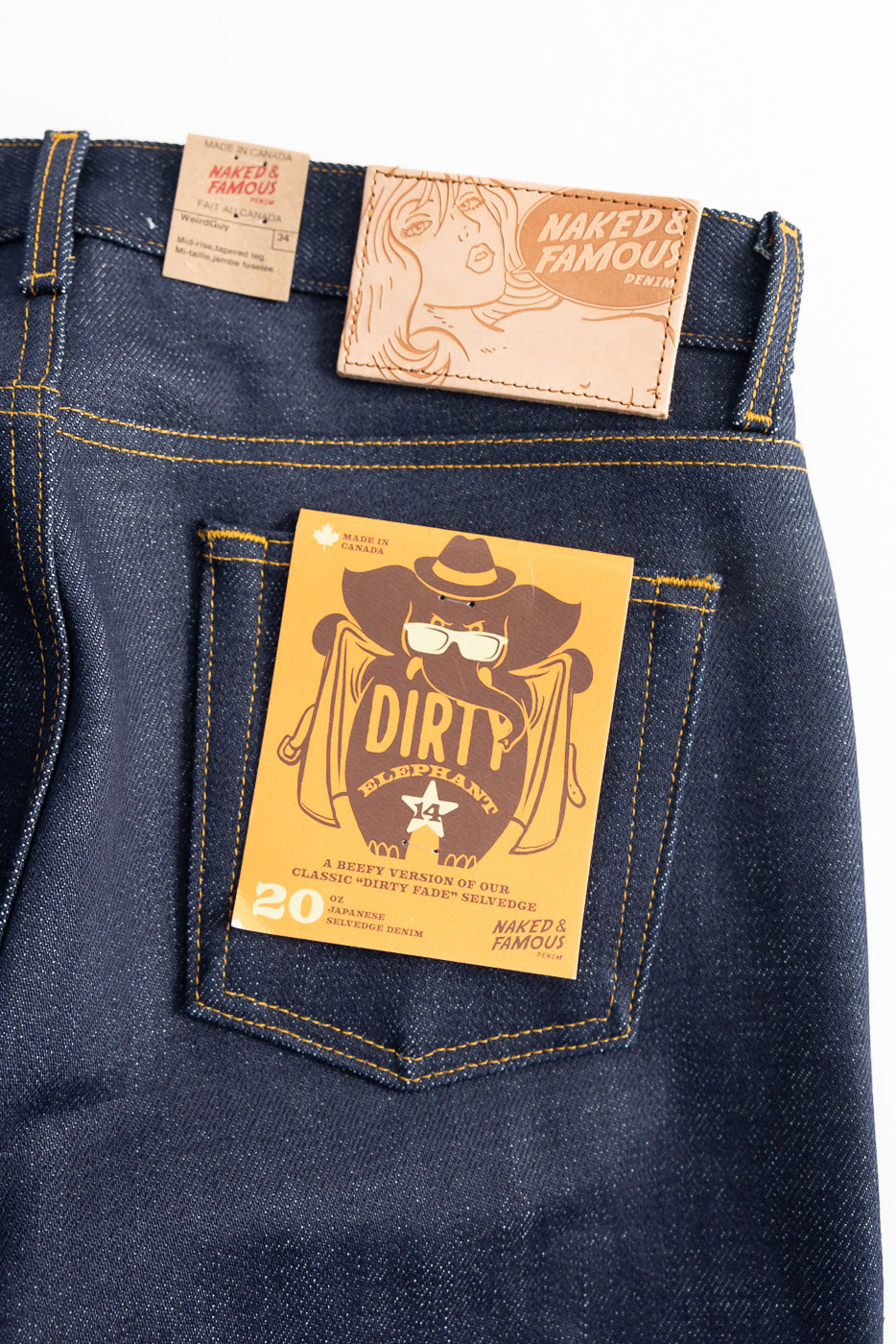 Close-up of Naked & Famous Dirty Elephant 14oz selvedge jeans, rear pocket detail with branded patch and product tag, showcasing Japanese denim texture.