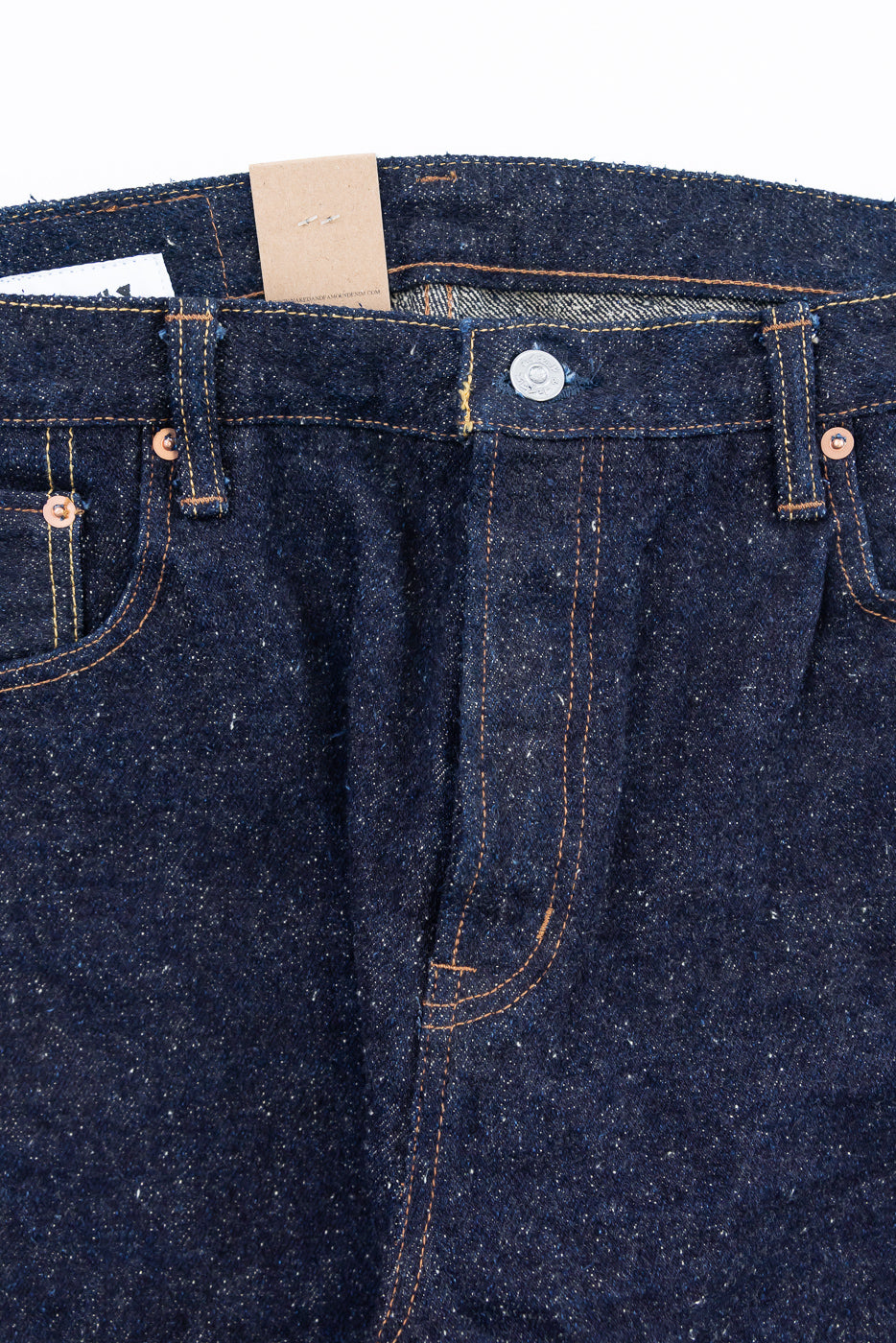 Close-up front view of Naked & Famous Genseki Selvedge jeans, button fly, raw denim texture, visible top button and coin pocket details.