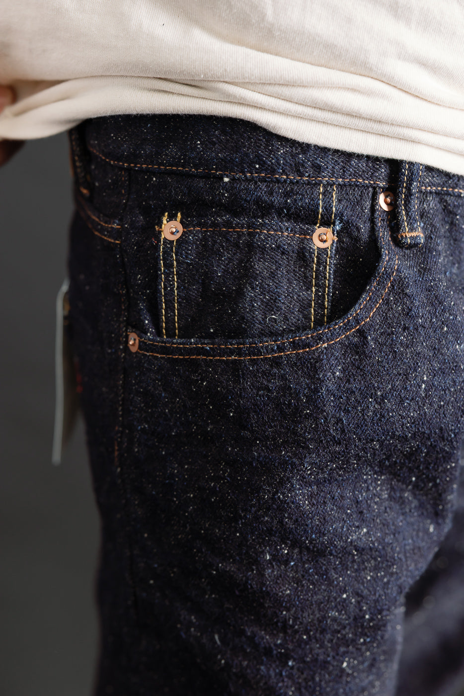 Close-up of front left pocket and textured dark indigo selvedge denim on male model, 5'9