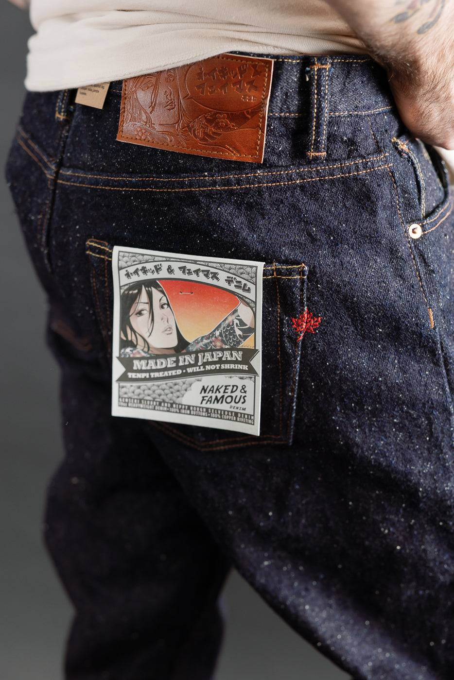 Close-up of Naked & Famous Genseki Selvedge denim back pocket, brown leather patch, on male model 5'9