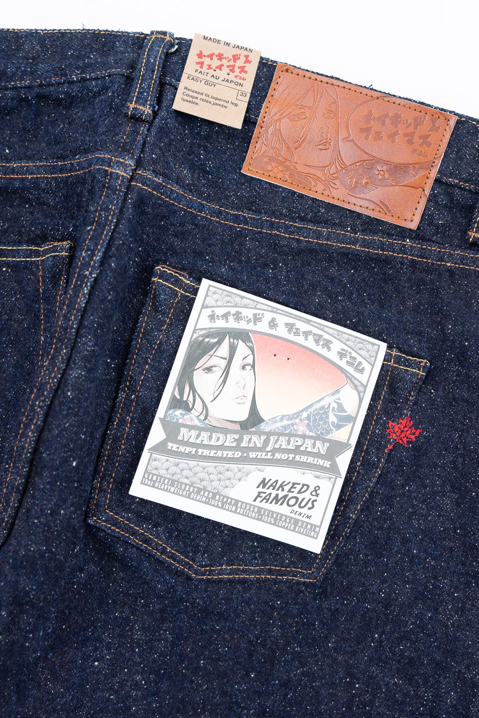 Close-up of back of Naked & Famous Easy Guy selvedge jeans, showing leather patch, rear pocket, and product tag details at Dant.