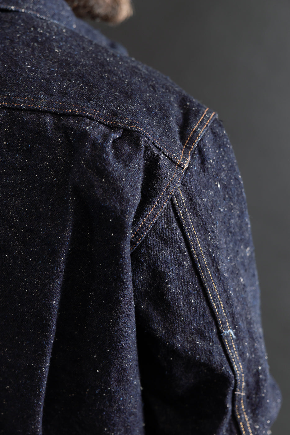 Close-up of Genseki Selvedge denim jacket shoulder, textured navy fabric and contrast stitching, back view