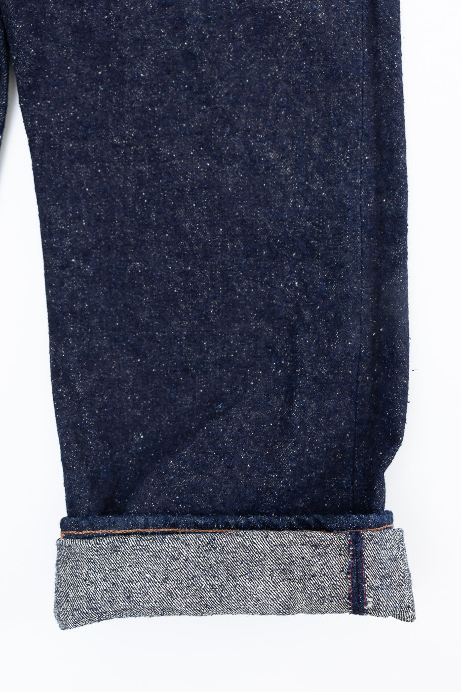 Close-up of cuffed leg hem on Naked & Famous Genseki Selvedge jeans, showing selvedge edge and dark indigo denim texture, front side.