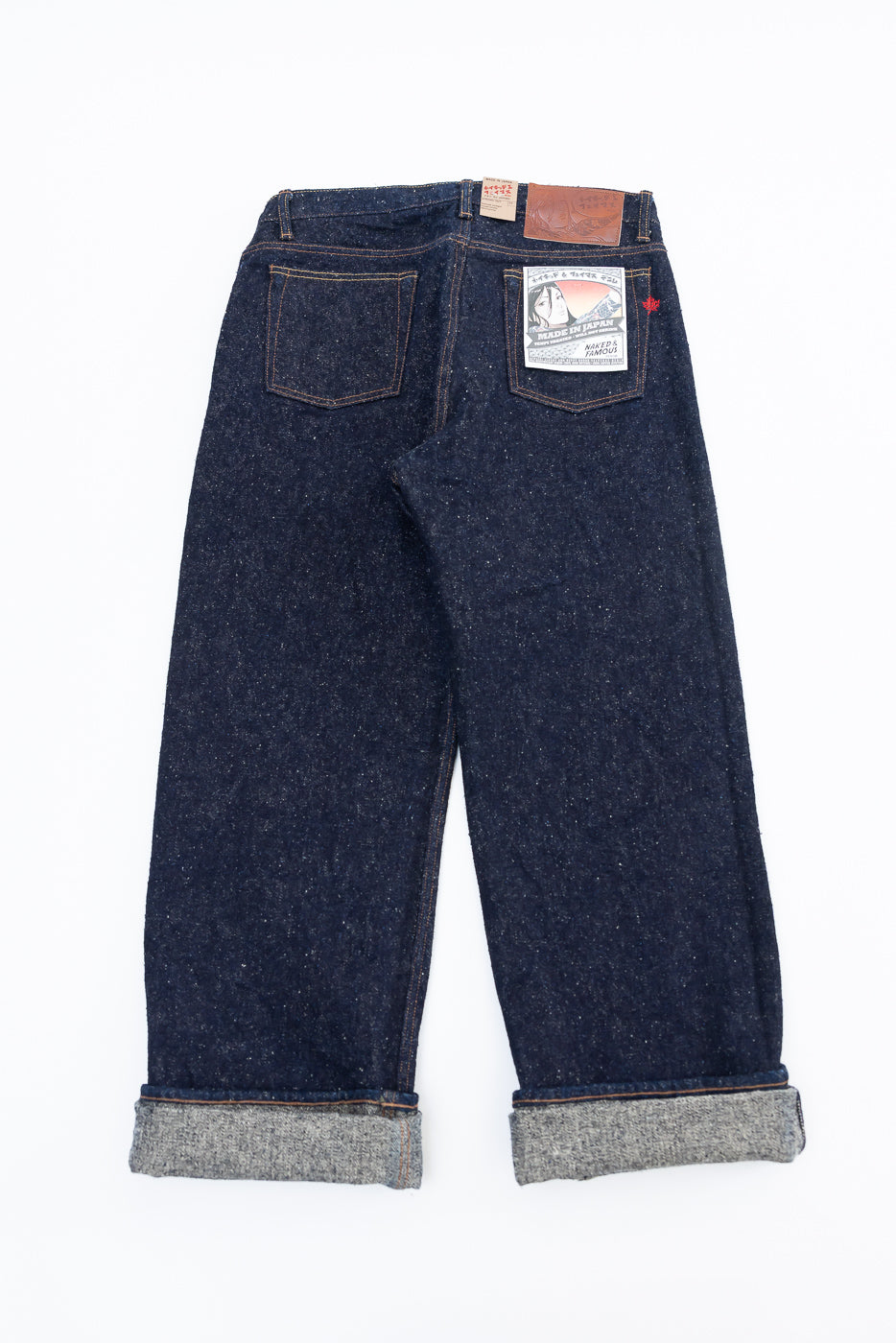 Back flat lay of Naked & Famous Genseki Selvedge jeans, showing rear pockets, labels, and cuffed hem.
