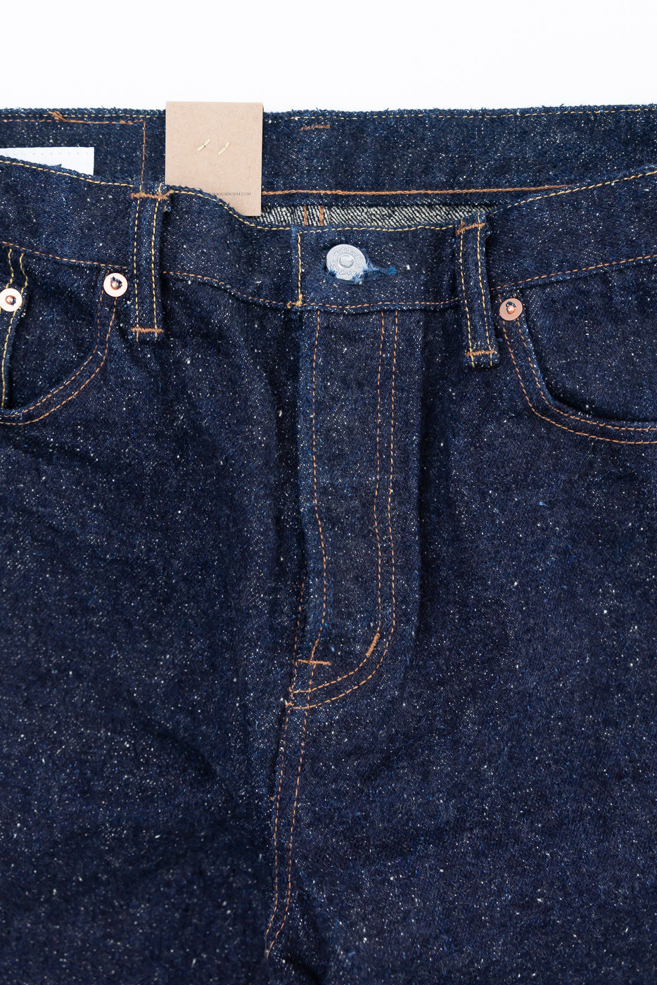 Close-up of front waist and pockets of Naked & Famous selvedge jeans, textured indigo denim, copper rivets.