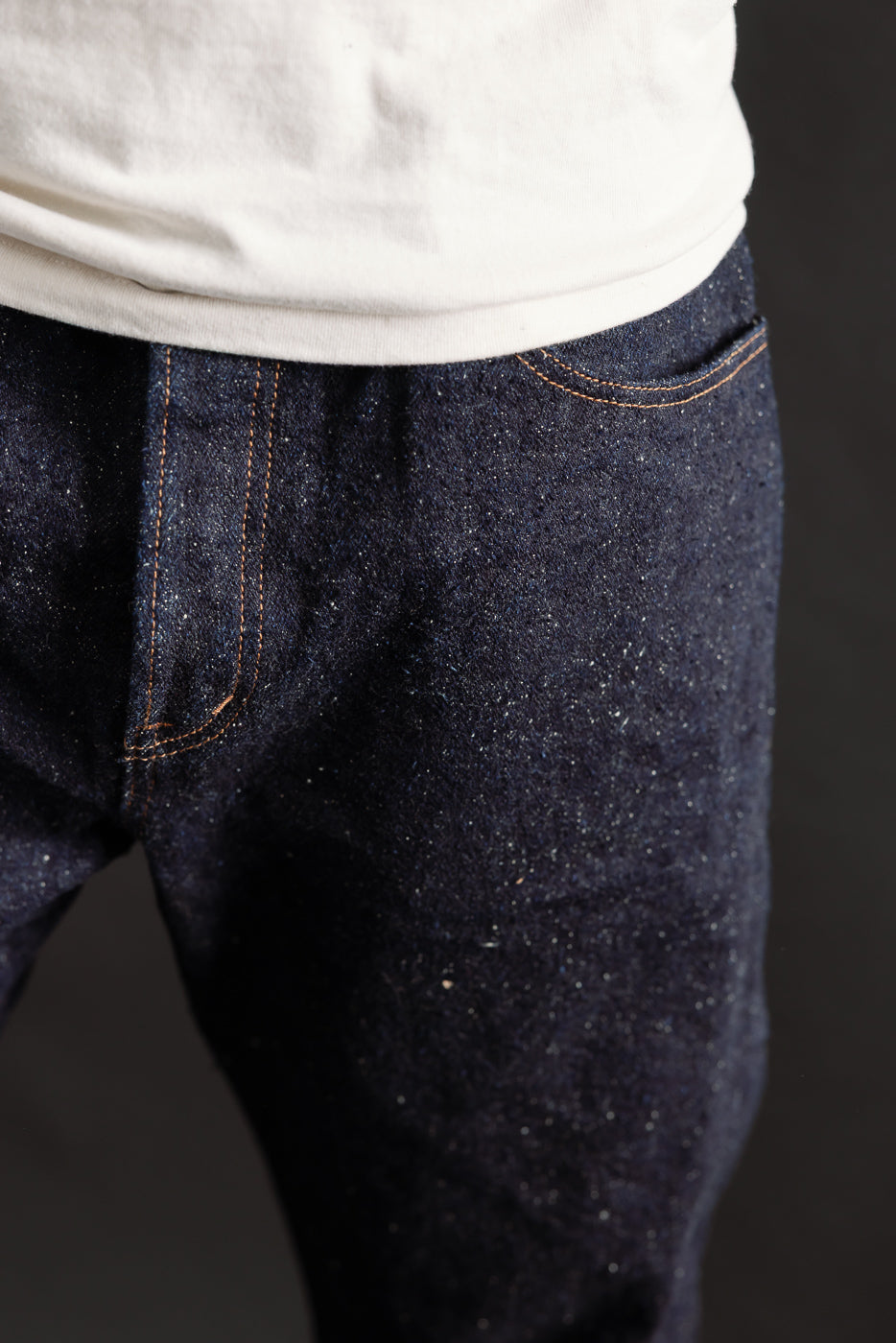 Close-up front detail of Naked & Famous selvedge denim jeans on male model, athletic build, showing texture and pocket stitching.