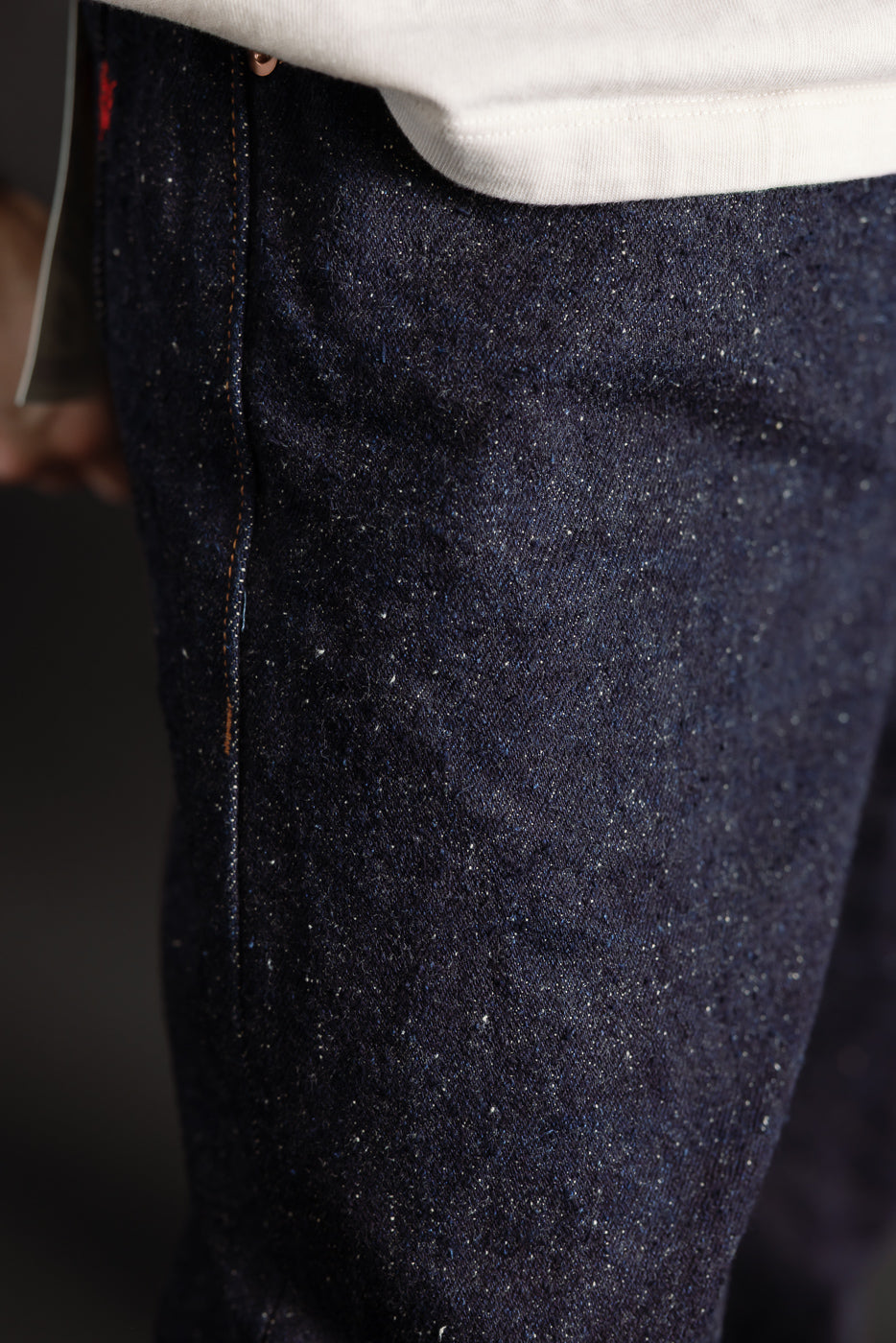 Close-up of front left thigh of Naked & Famous Genseki Selvedge denim on male model, showing indigo fabric texture and stitching detail at Dant Indianapolis.