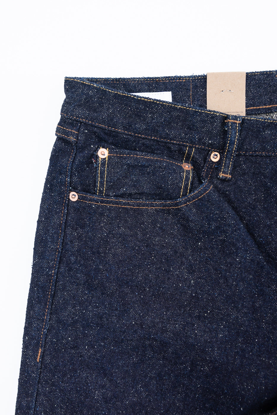 Close-up of front waist and pocket on Naked & Famous Genseki Selvedge jeans, dark indigo denim texture, copper rivets, visible at Dant contemporary casual apparel.