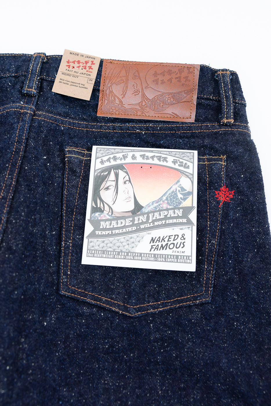 Close-up of Naked & Famous Genseki Selvedge Weird Guy jeans back with leather patch, tags, and visible denim texture.