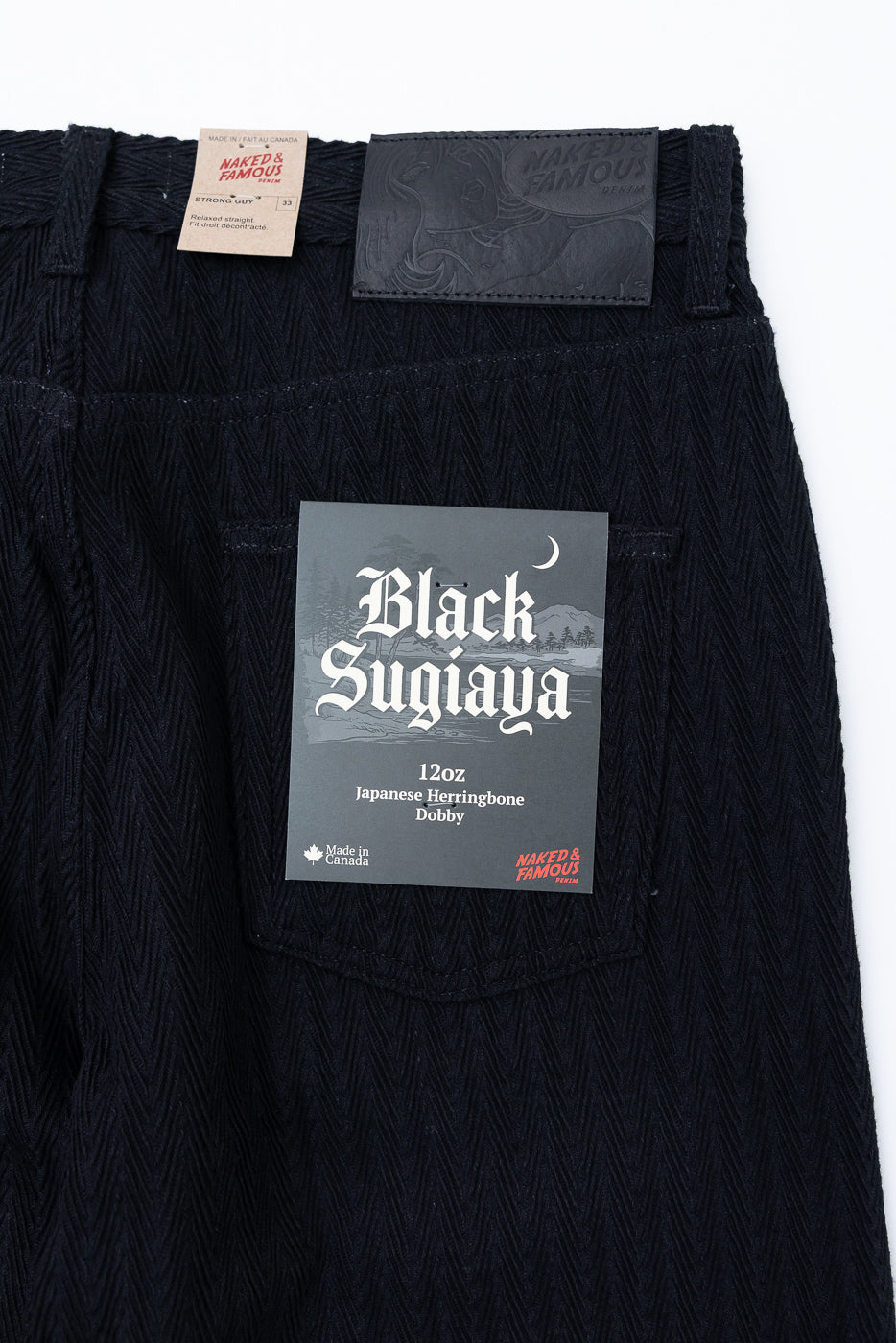 Close-up back view of black Japanese herringbone dobby fabric texture on denim pants.
