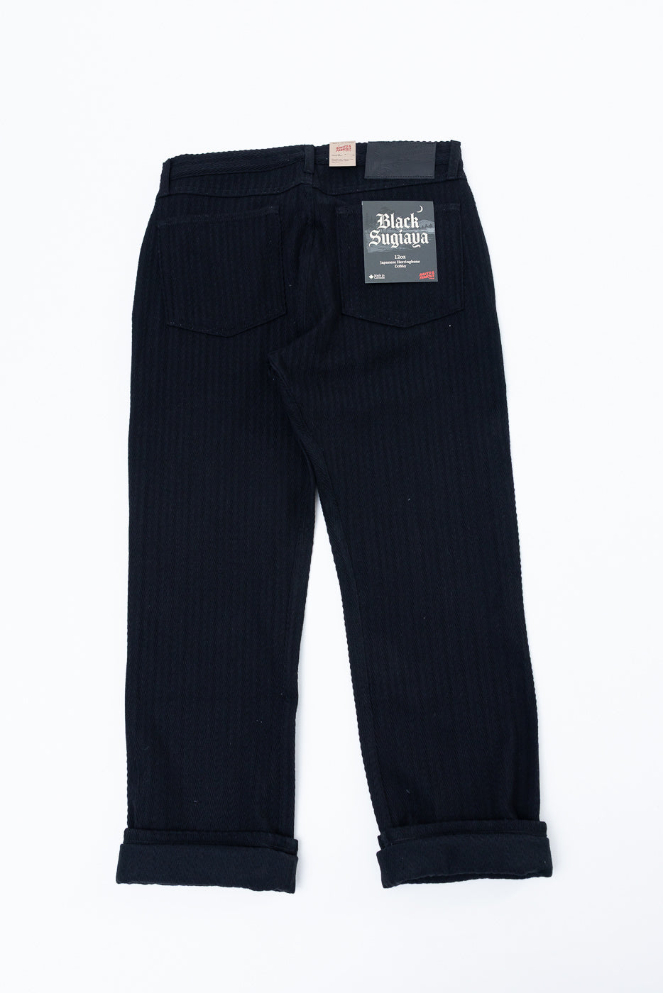 Back view flat lay of black corduroy trousers showing rear pockets and waistband detail.