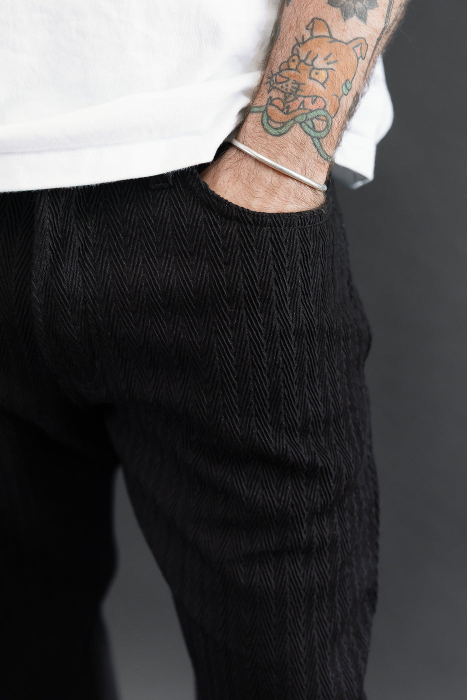 Close-up side view of black textured trousers on a male model, 5'9