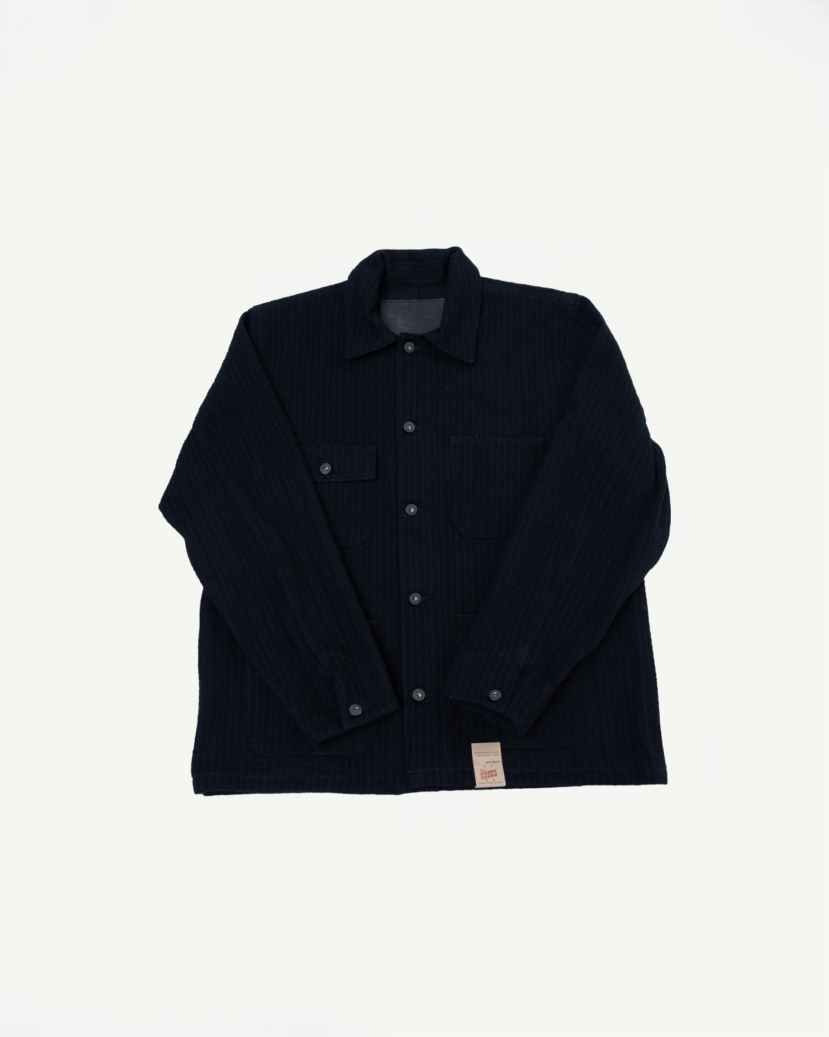 Front view flat lay of a black textured button-up shirt with chest pockets and hem tag.