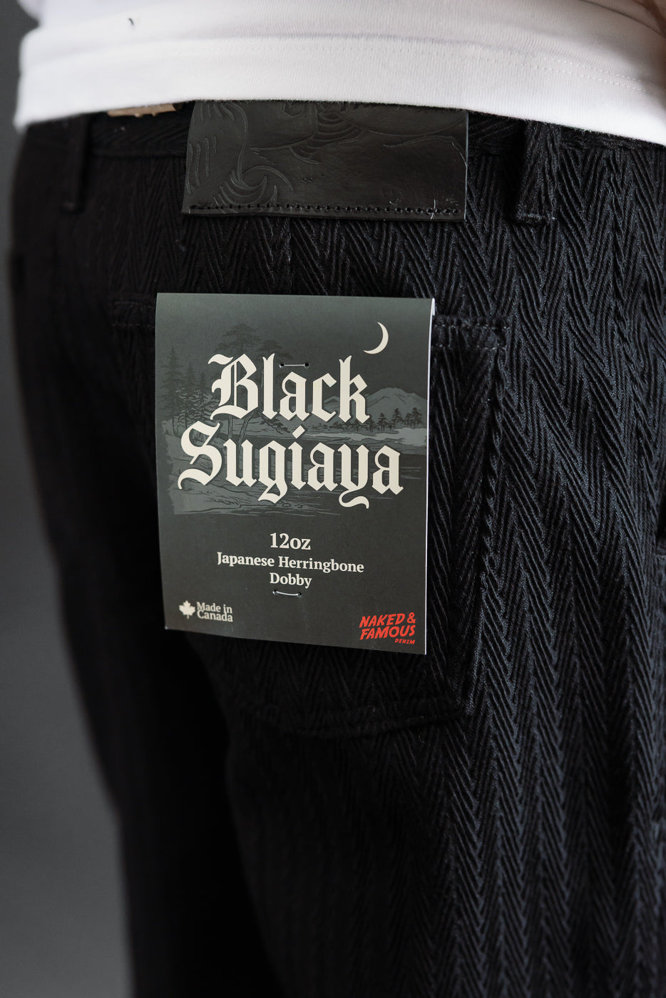 Close-up back view of black 12oz Japanese herringbone dobby fabric on a pair of trousers.