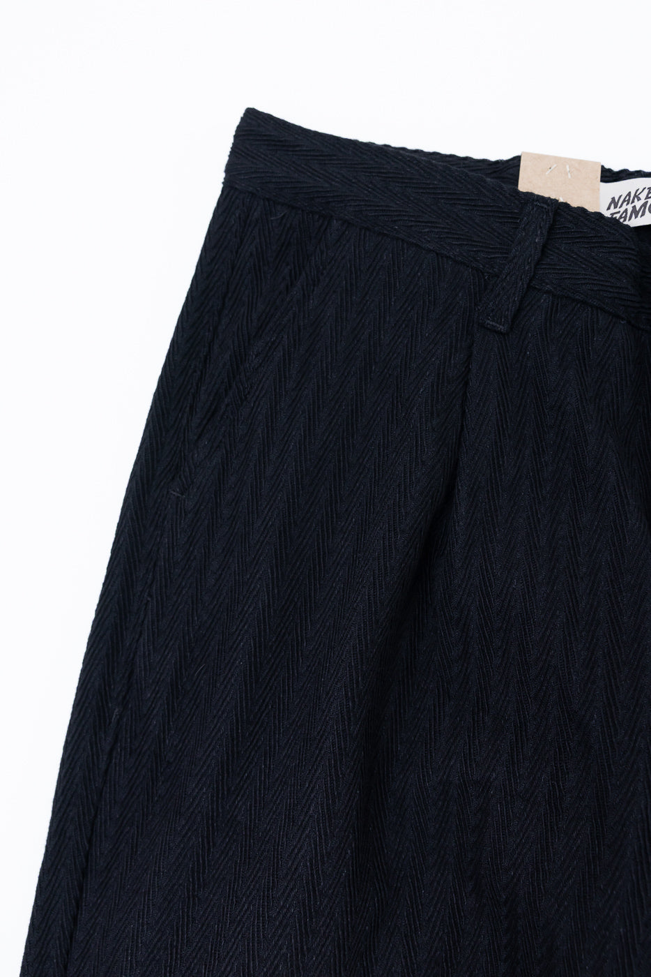 Close-up of the front waistband and textured herringbone fabric of black trousers.