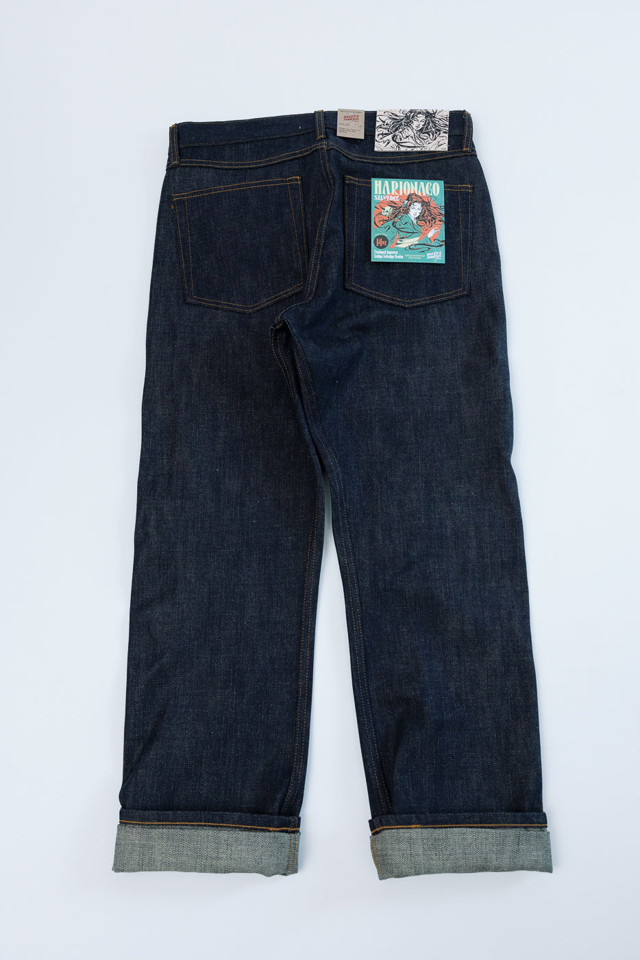 Back view of dark selvedge jeans with rolled hems and branded patch on rear pocket