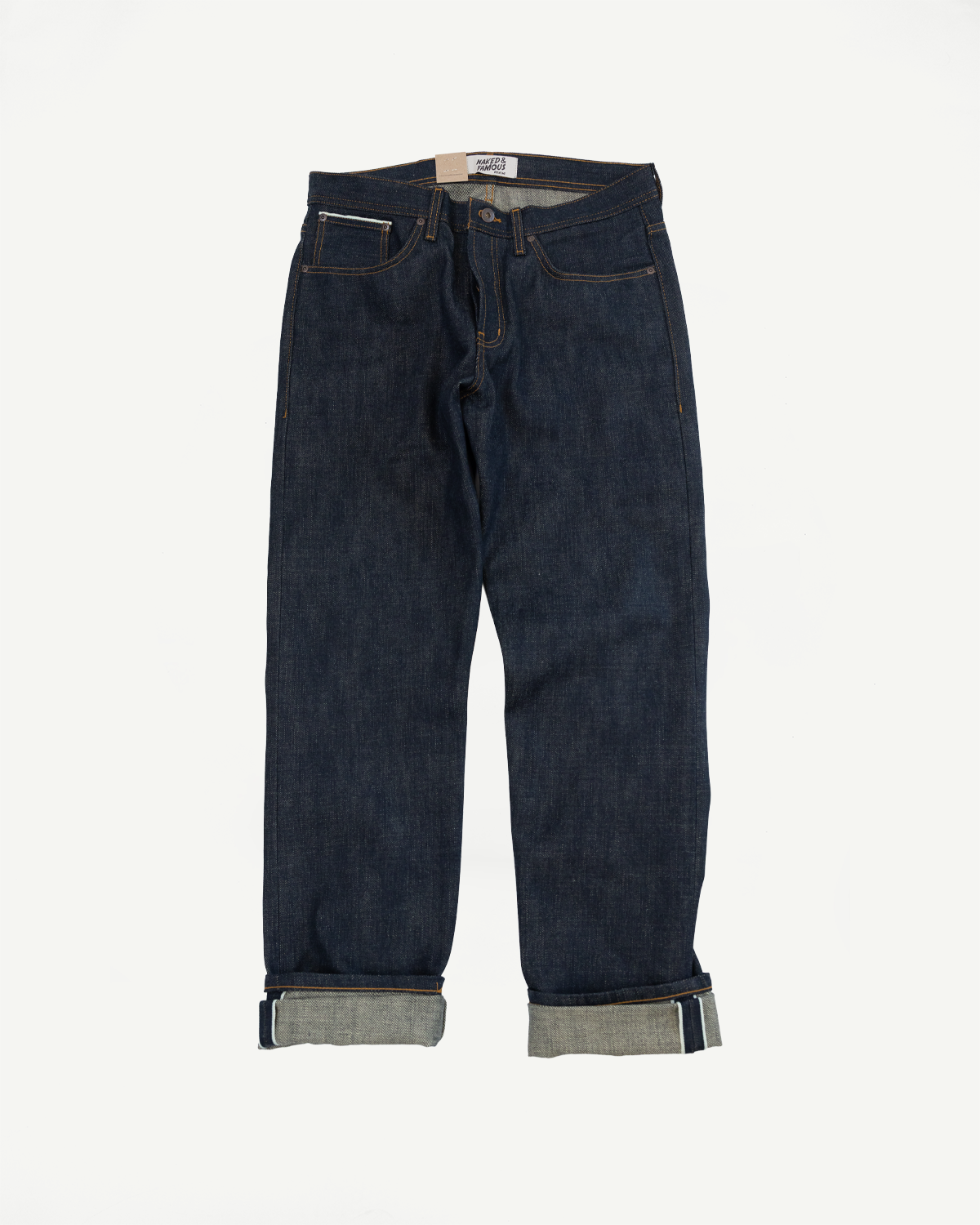 Front flat lay of dark selvedge denim jeans with cuffed hems, orange stitching, and visible brand tag