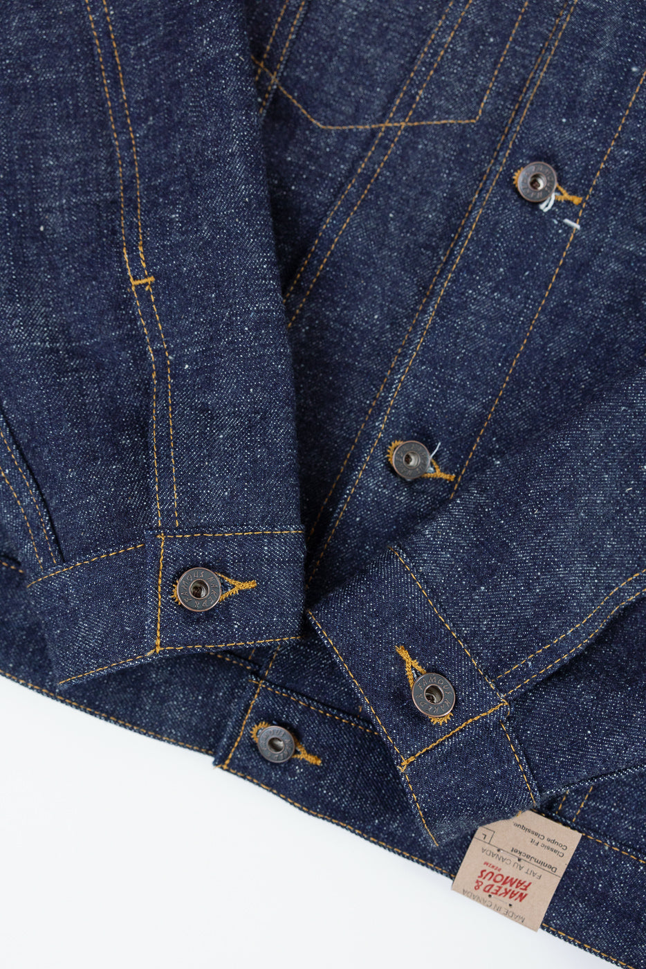 Close-up front view of raw denim jacket with copper buttons, contrast stitching, and brand tag detail