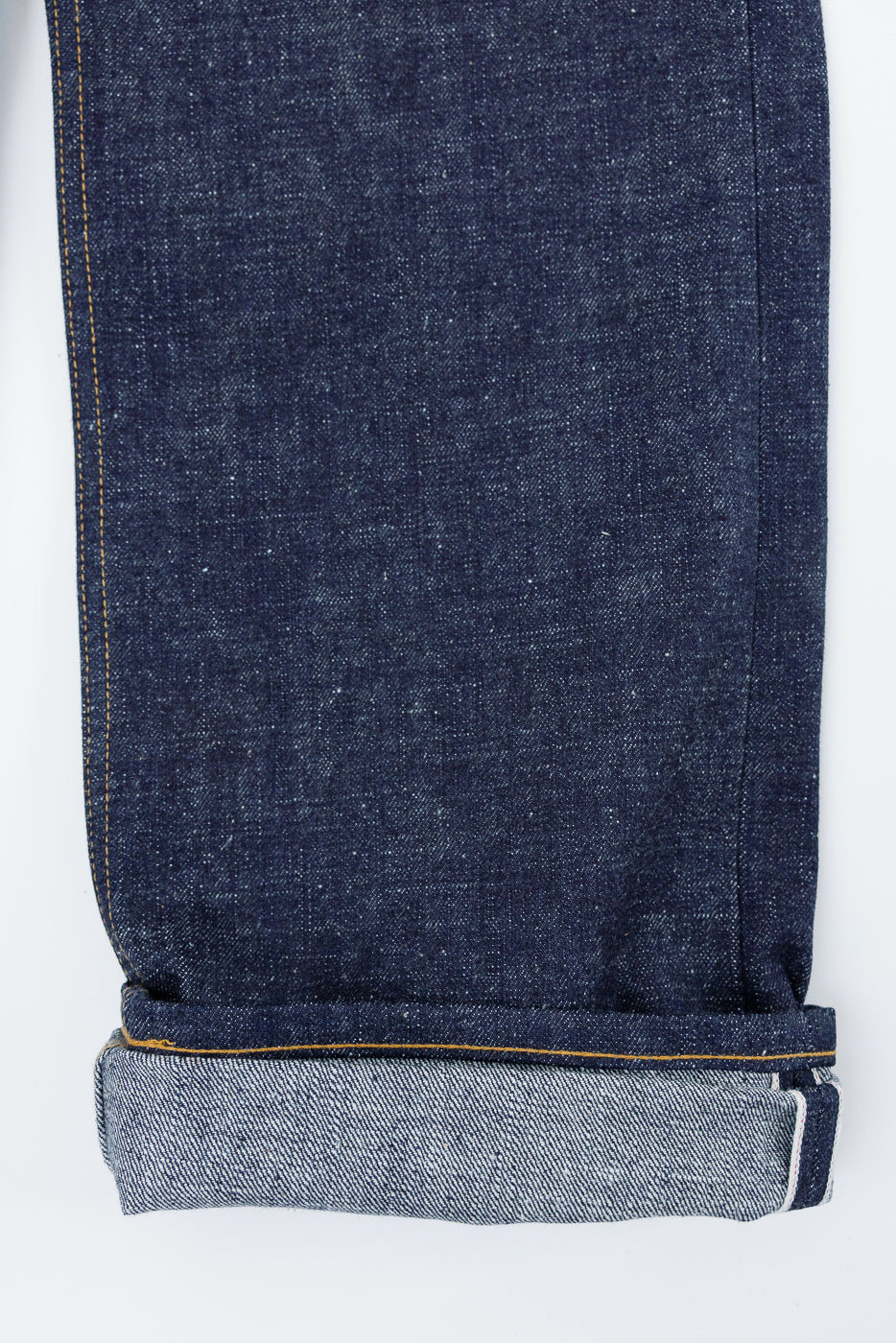 Close-up of selvedge denim jeans showing front hem with rolled cuff and contrast stitching