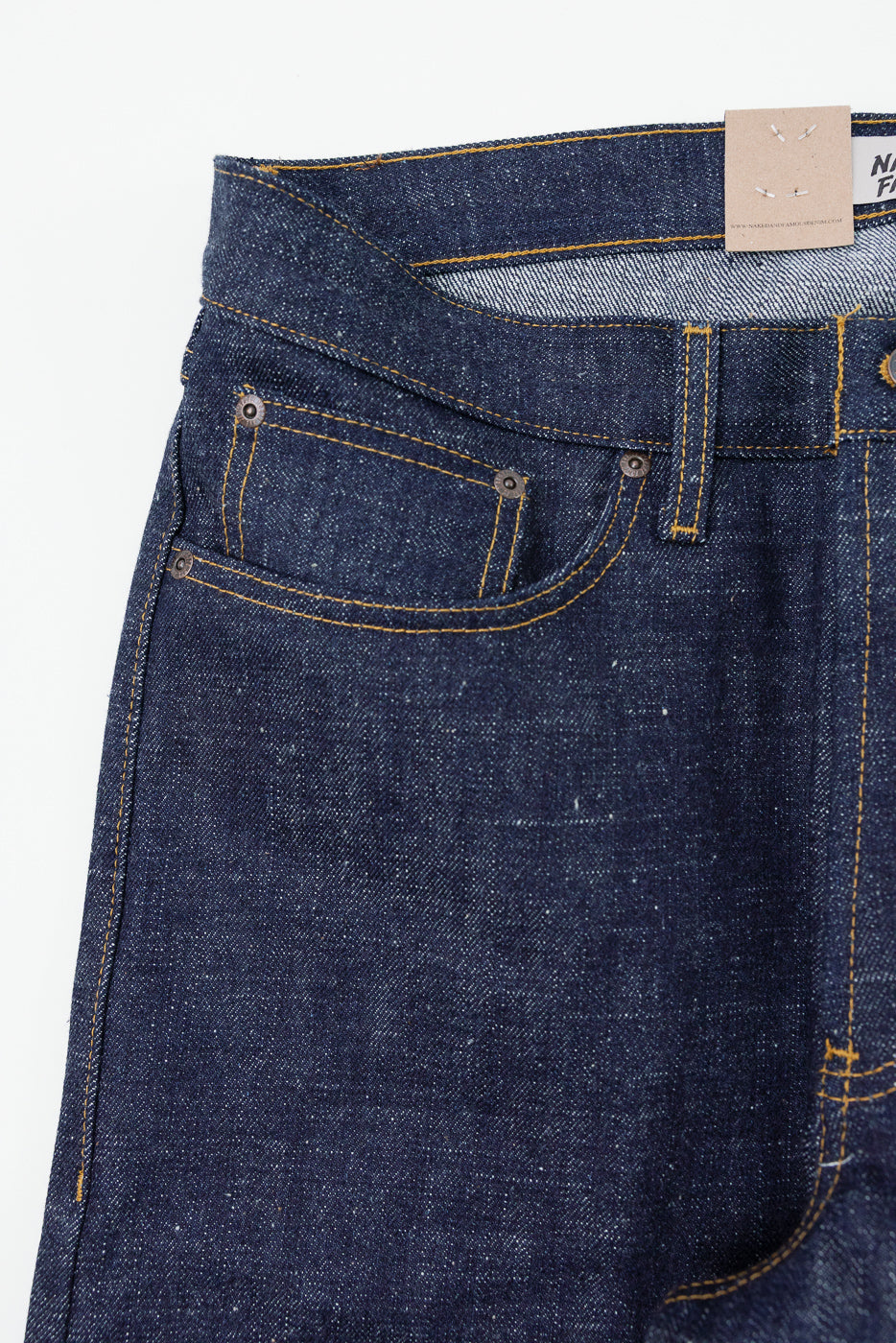 Close-up front view of raw selvedge denim jeans with gold stitching, button fly, and brand tag detail