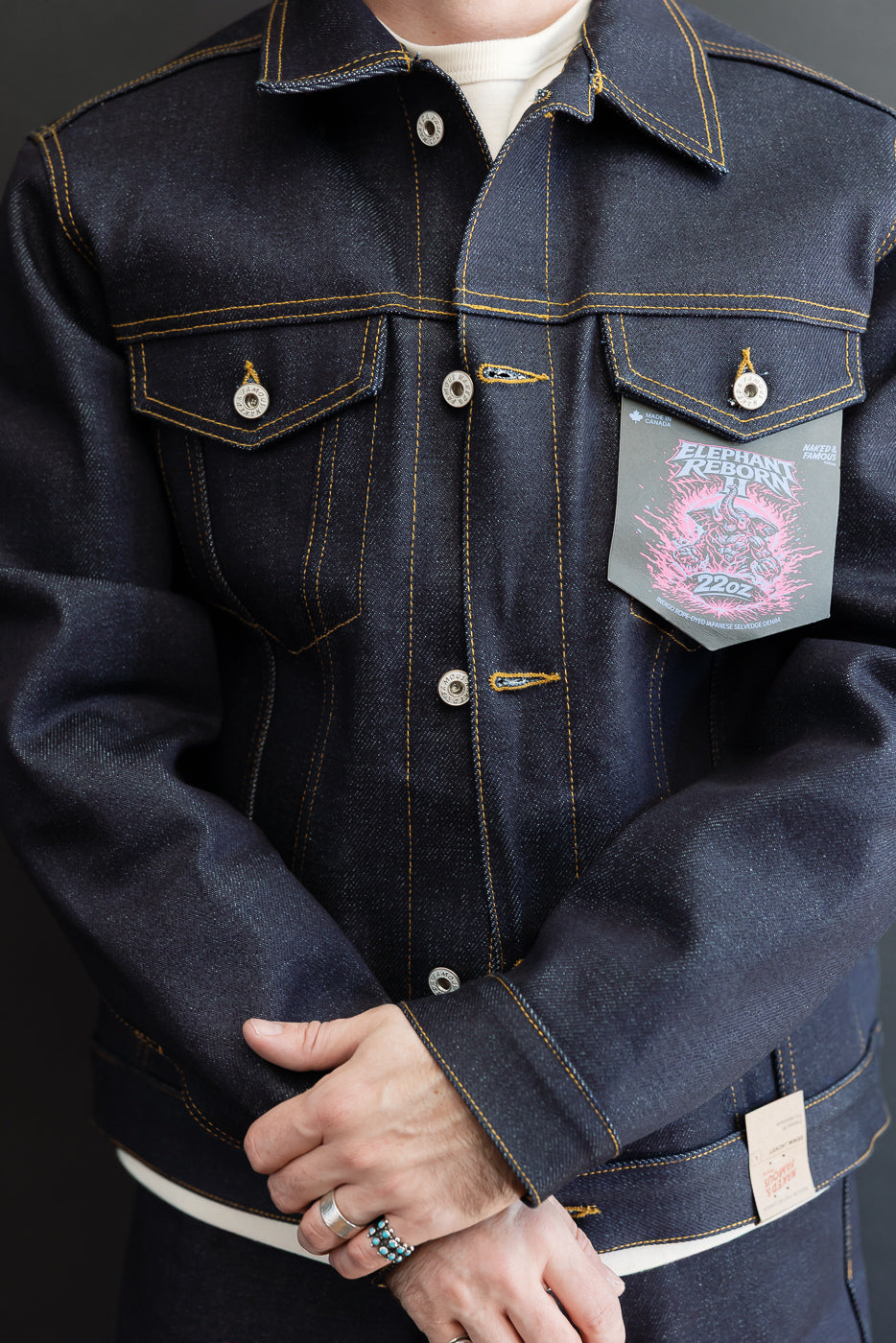 Close-up front view of a dark indigo denim jacket on a male model, 5'9