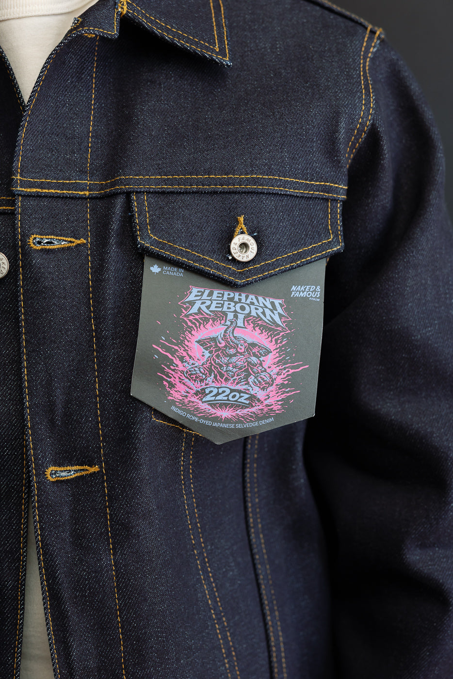 Close-up of the front left chest pocket and button detail on a dark indigo selvedge denim jacket.