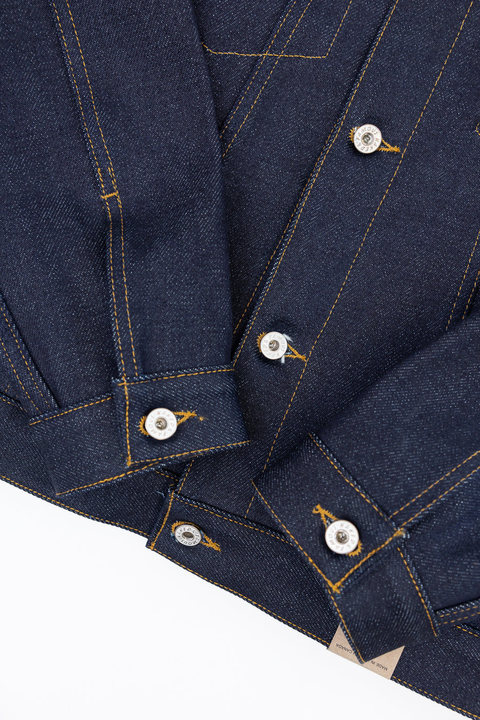 Close-up of front navy denim shirt showing gold stitching, buttons, and fabric texture.