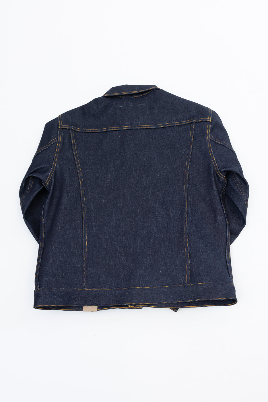Back view of a dark indigo selvedge denim jacket flat lay.