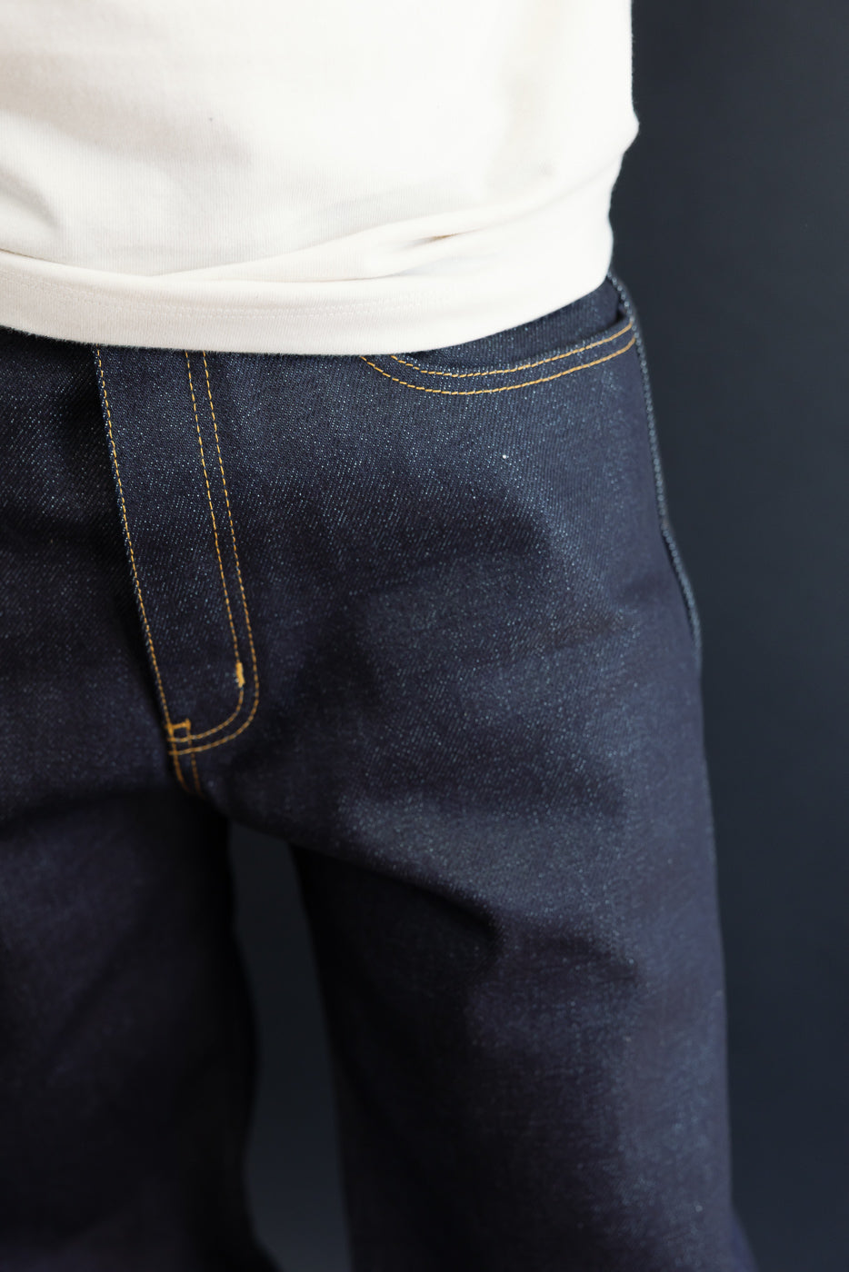 Close-up of the front right hip and pocket area of dark indigo selvedge denim jeans.