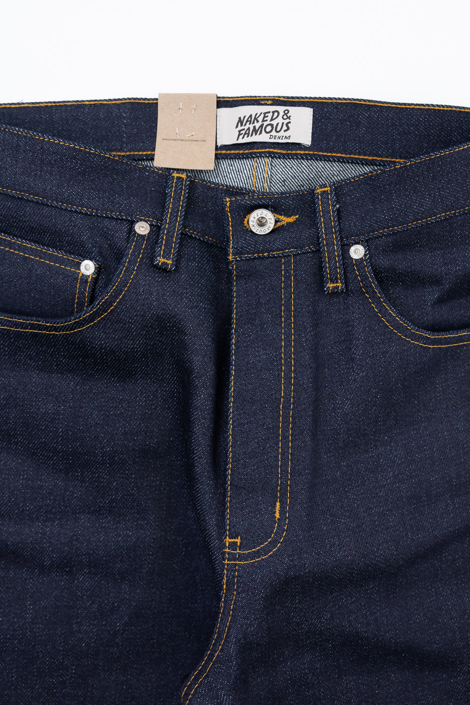 Close-up front view of dark indigo denim jeans showing waistband, button, and gold stitching.