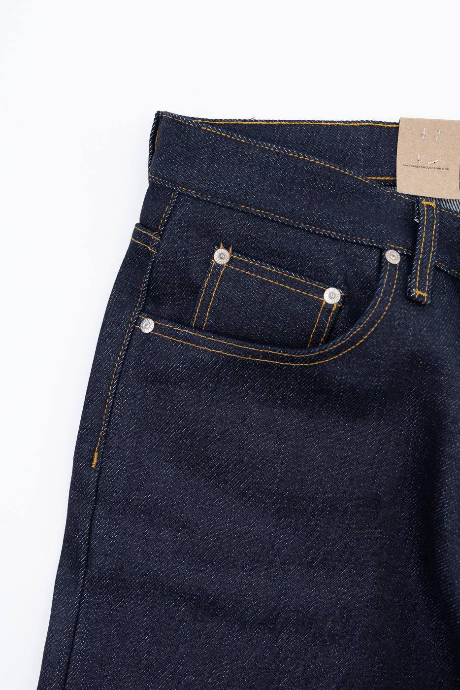 Close-up front view of dark indigo selvedge denim jeans showing pocket stitching and rivets.